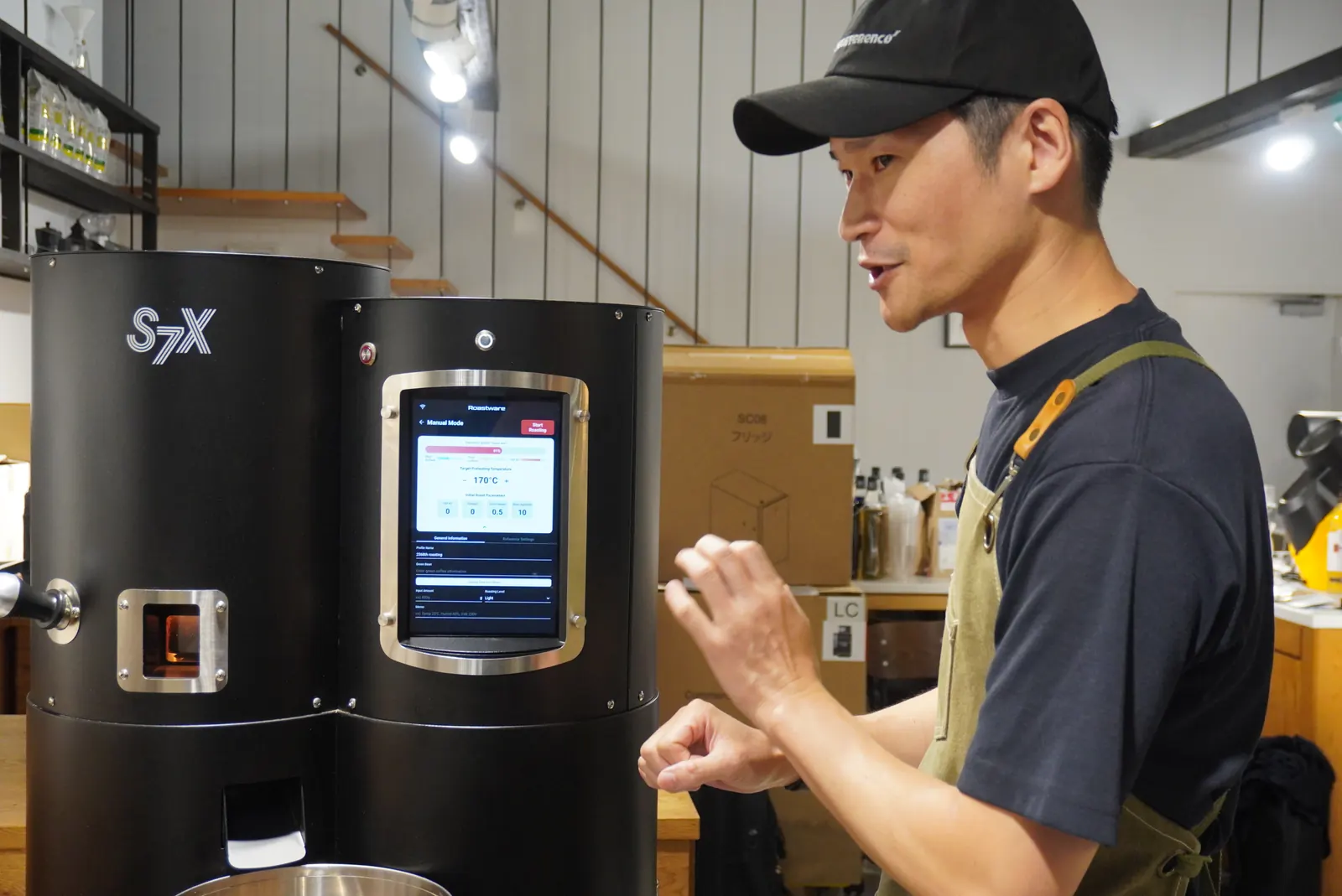 焙煎機の前で説明する三戸さん